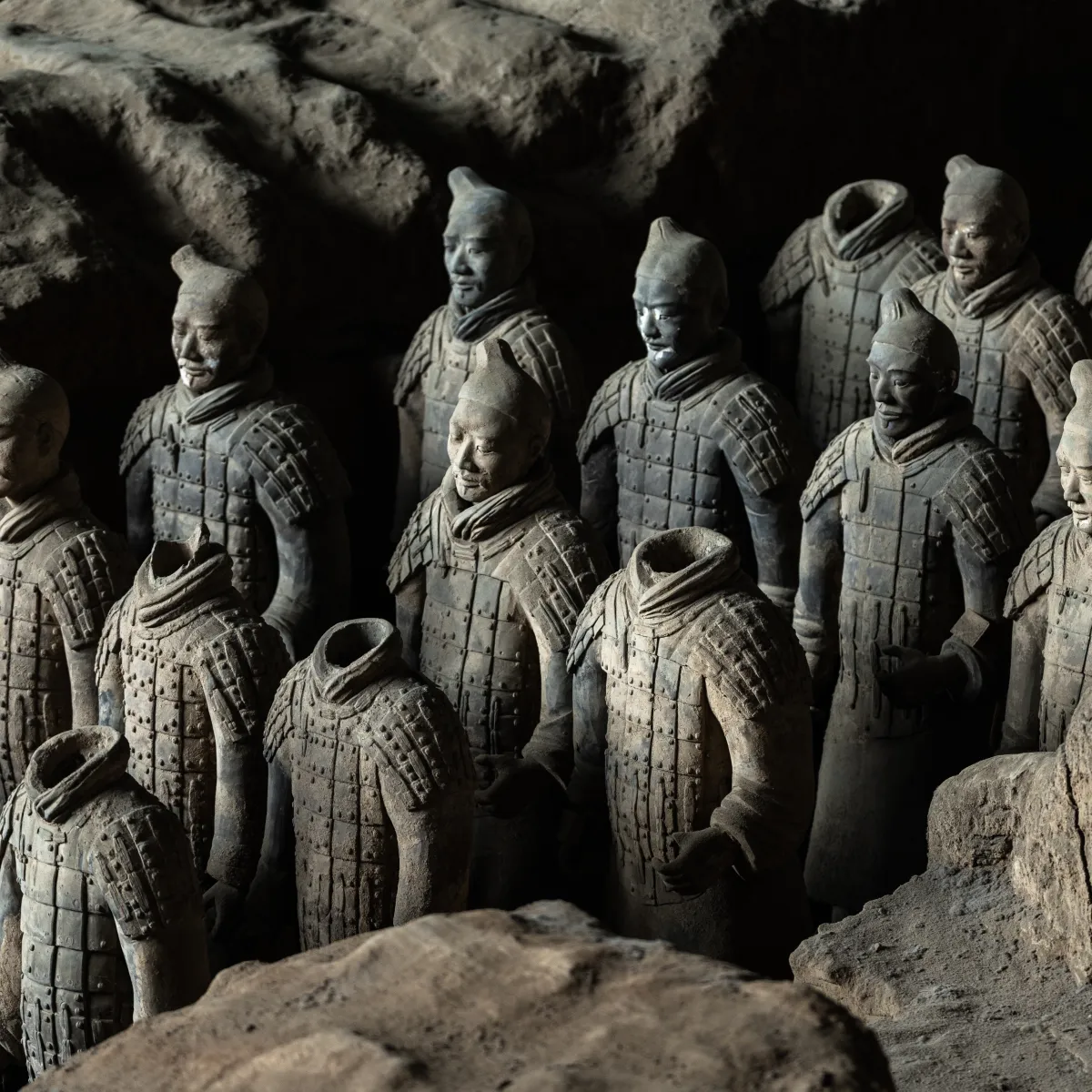 XIAN, CHINA - OCTOBER 28, 2025: Partially restored and damaged Terracotta Warriors seen in a darkened section of the Pit 1 excavation site, highlighting the ongoing preservation work.